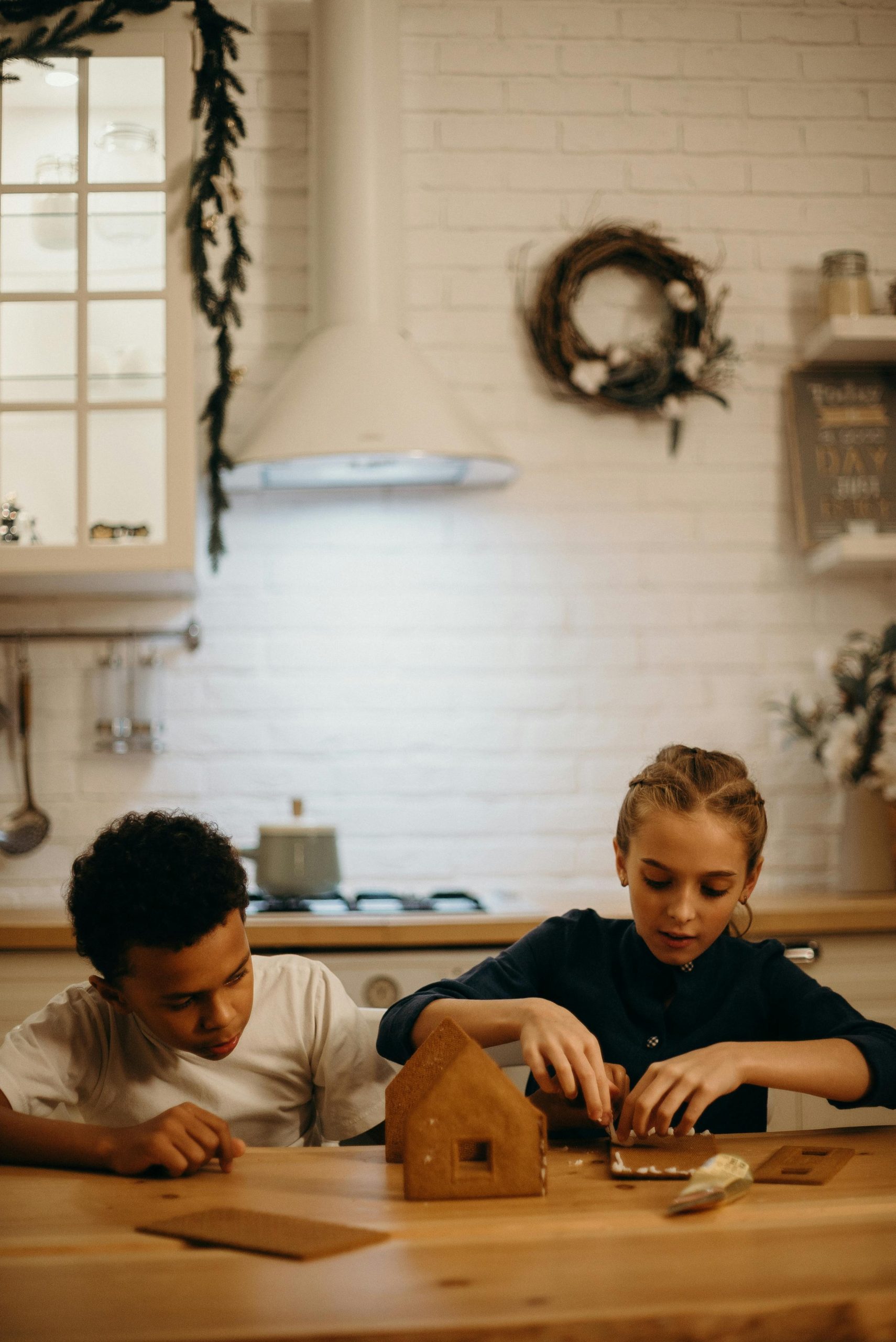 Two children joyfully building a gingerbread house together in a warmly lit kitchen, capturing a festive holiday spirit. Deux enfants construisant joyeusement une maison en pain d'épice ensemble dans une cuisine chaleureusement éclairée, capturant l'esprit festif des fêtes.
