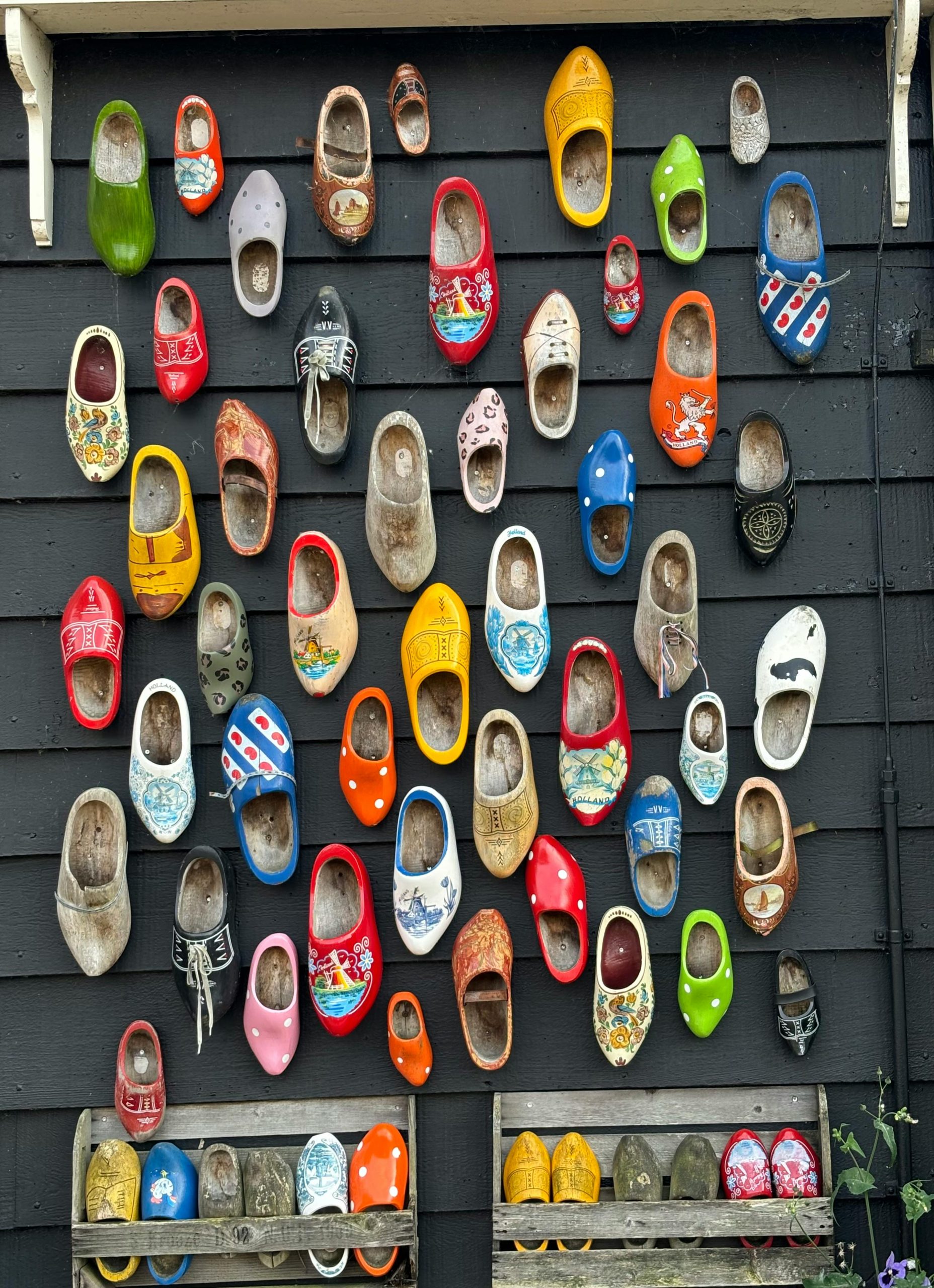 A vibrant display of traditional wooden clogs on a wall in Zaandam, Netherlands. Un vibrant étalage de sabots en bois traditionnels sur un mur à Zaandam, aux Pays-Bas.
