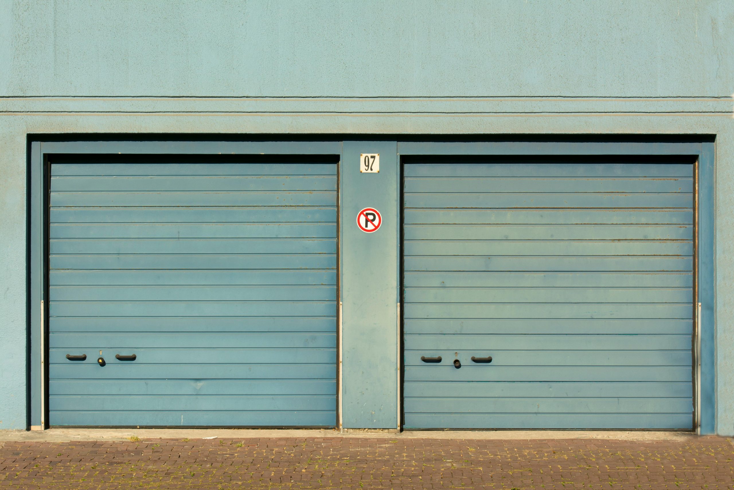 Porte de garage bleue avec un panneau "stationnement interdit" peint en extérieur.