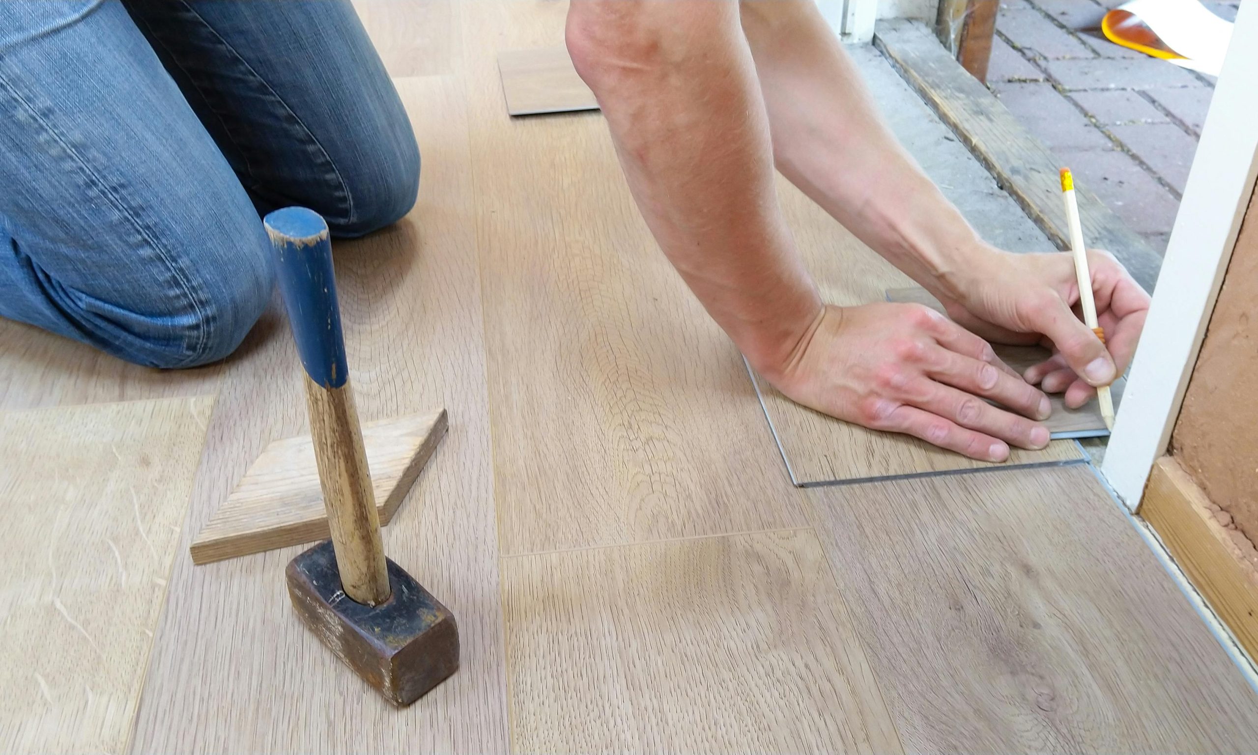 Un artisan mesure et marque soigneusement des panneaux de parquet pour une installation précise.