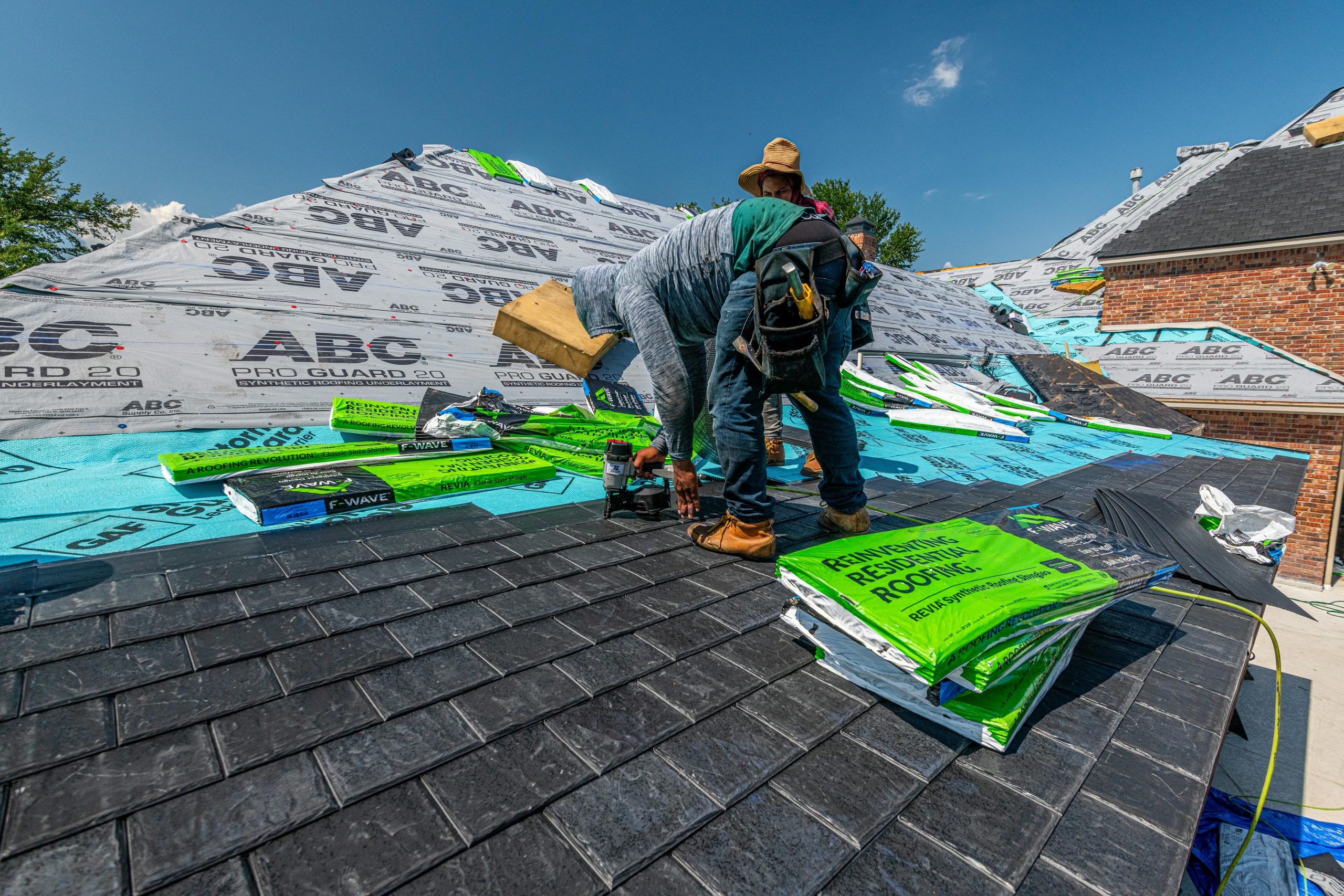 Workers installant un toit en ardoise synthétique sur une maison en brique à Fort Worth, Texas.