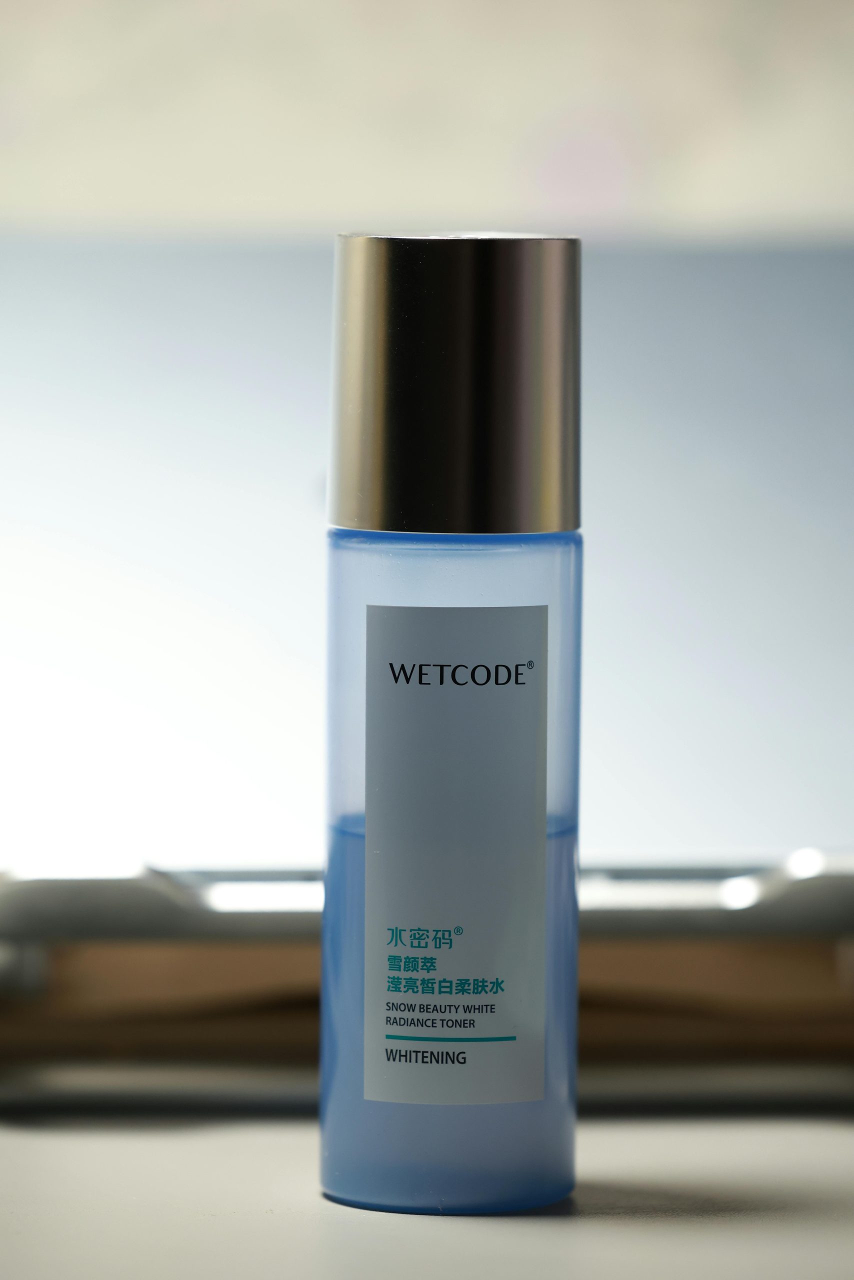 Close-up of a Wetcode Whitening toner bottle on a table under soft light. Gros plan d'une bouteille de tonique blanchissant Wetcode sur une table sous une lumière douce.
