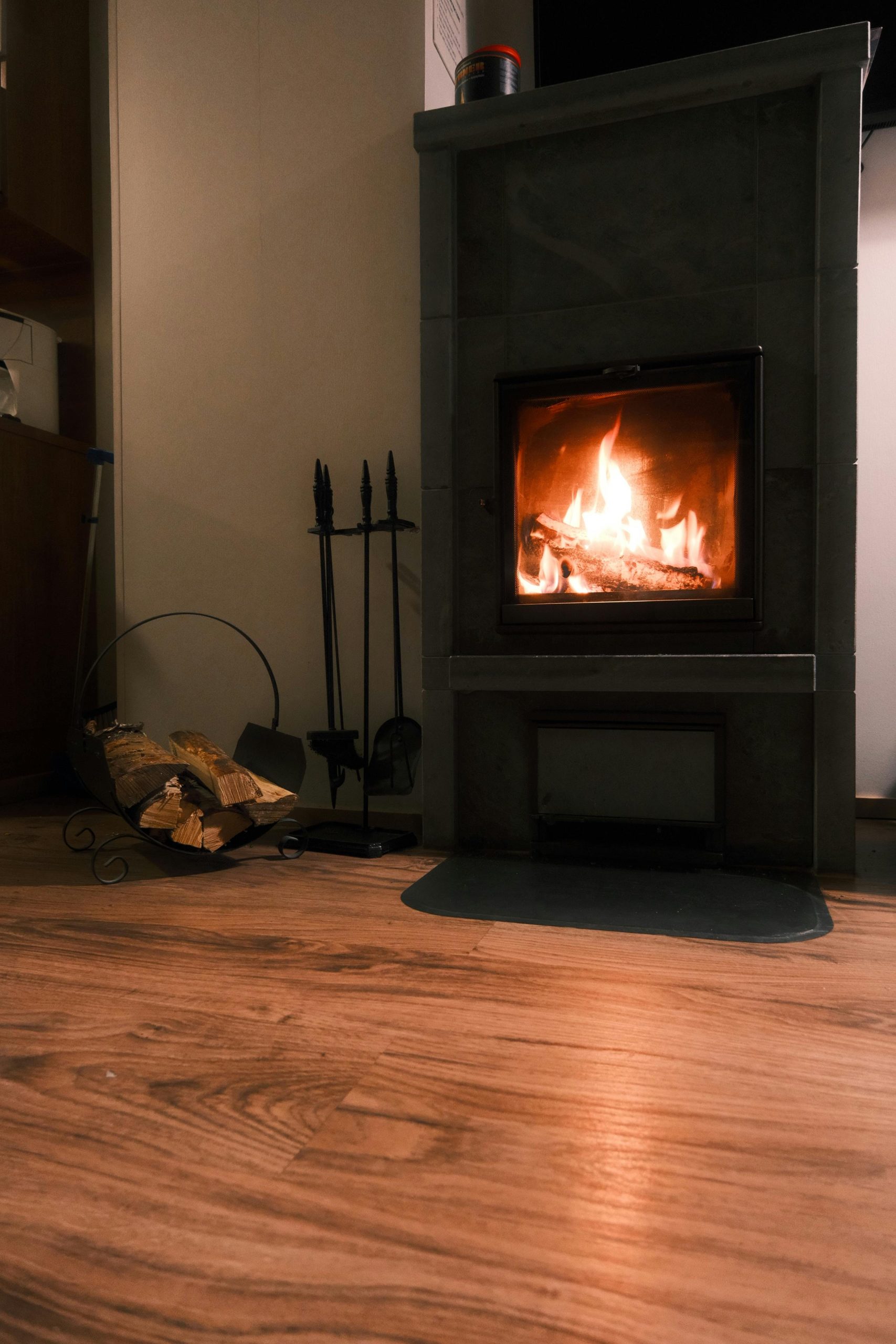 A warm indoor fireplace with logs and tools, perfect for a cozy ambiance. Un foyer intérieur chaleureux avec bûches et outils, parfait pour une ambiance douillette.