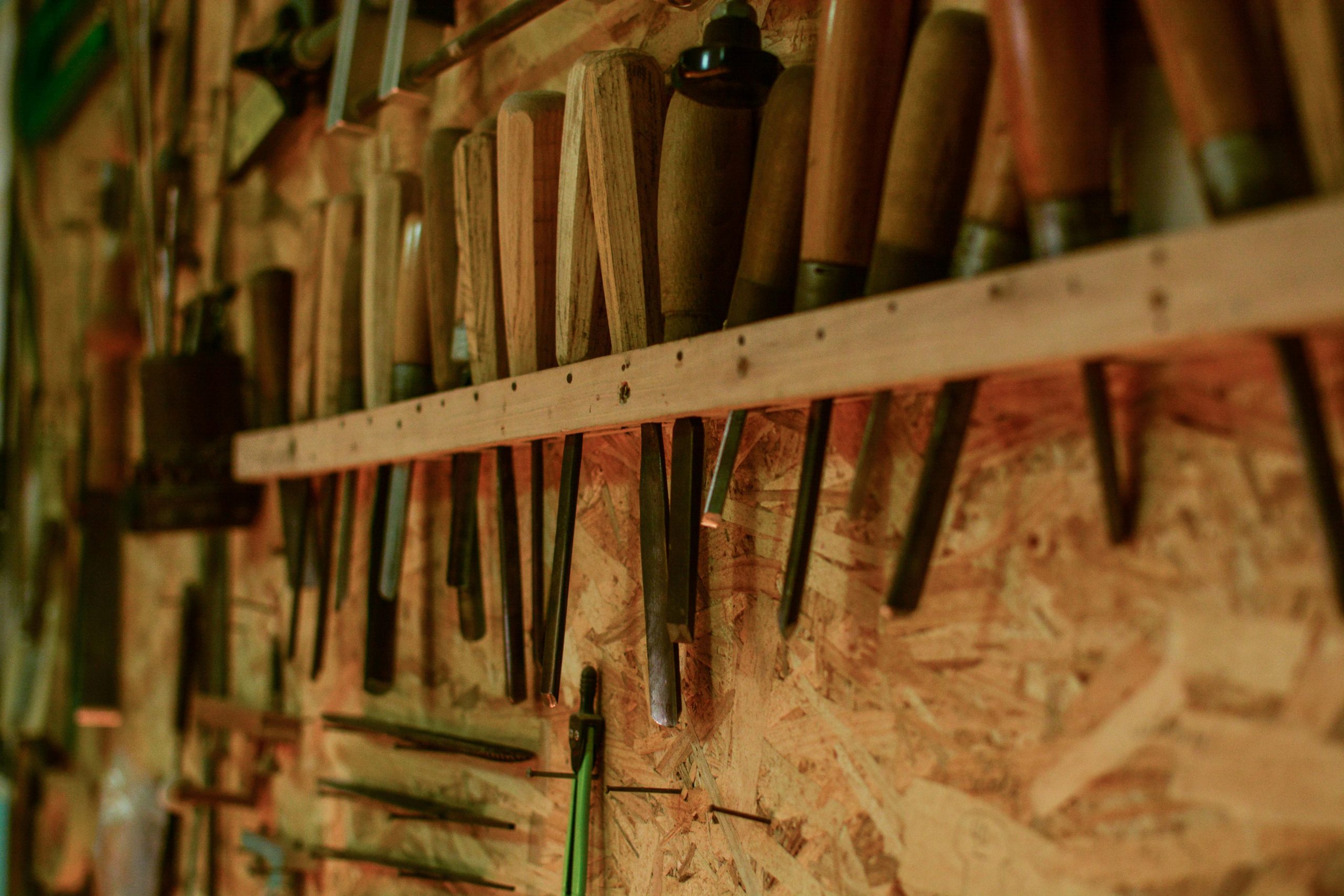 A collection of chisels and wood carving tools organized in a workshop setting. Une collection de ciseaux et d'outils de sculpture sur bois organisés dans un cadre d'atelier.