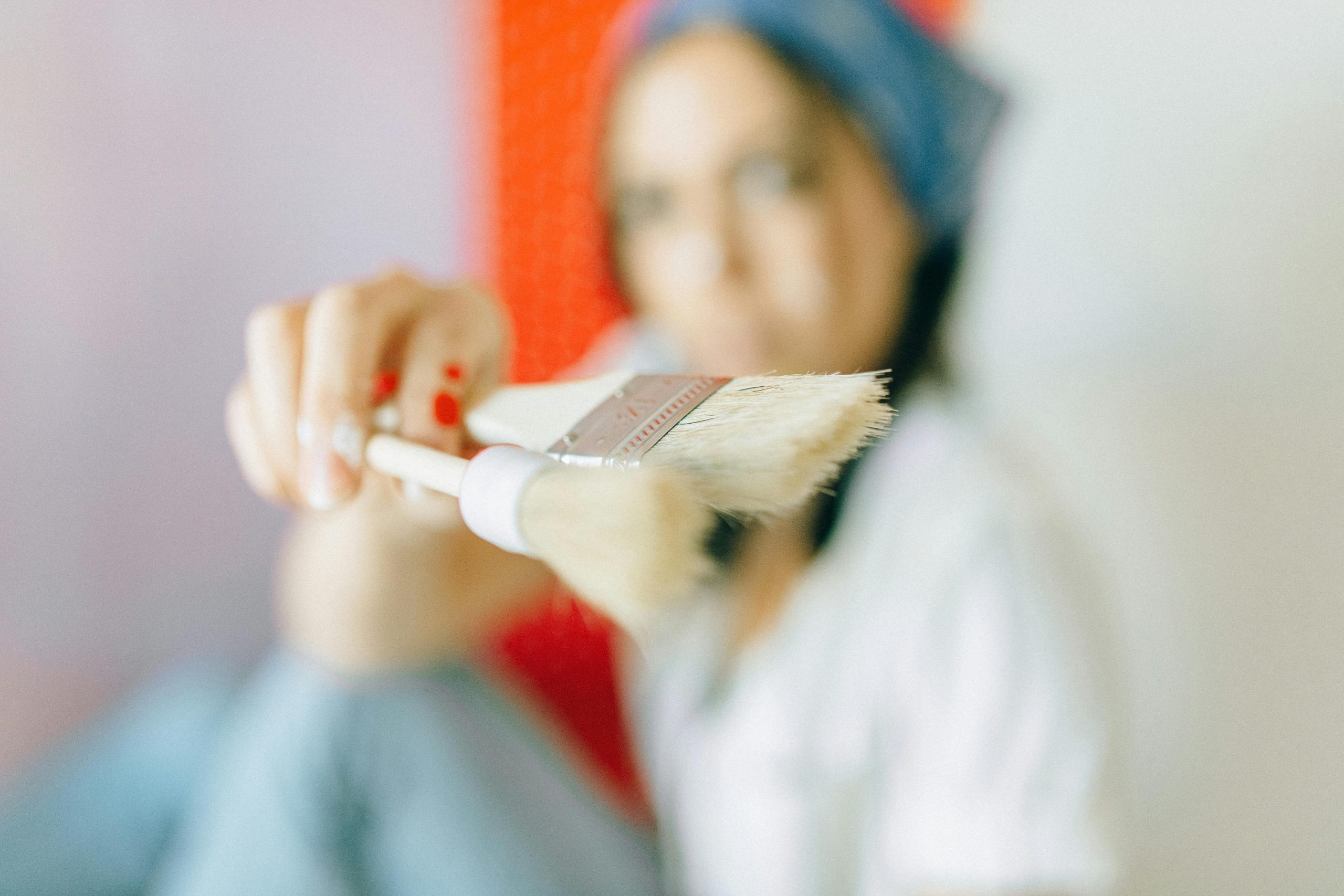 Artistic shot of a woman holding a brush, focusing on creative expression and painting tools. Un gros plan artistique d'une femme tenant un pinceau, mettant l'accent sur l'expression créative et les outils de peinture.