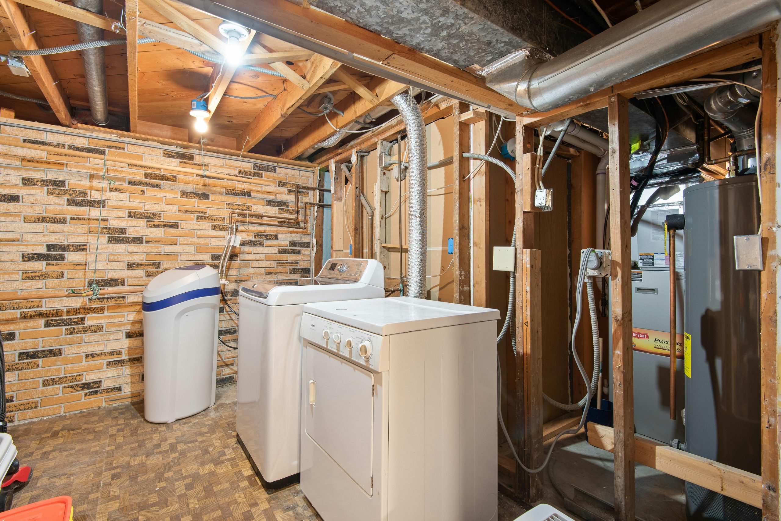 Spacious basement laundry room featuring modern appliances and exposed brickwork. Salle de buanderie spacieuse au sous-sol avec appareils modernes et briquetage apparent.