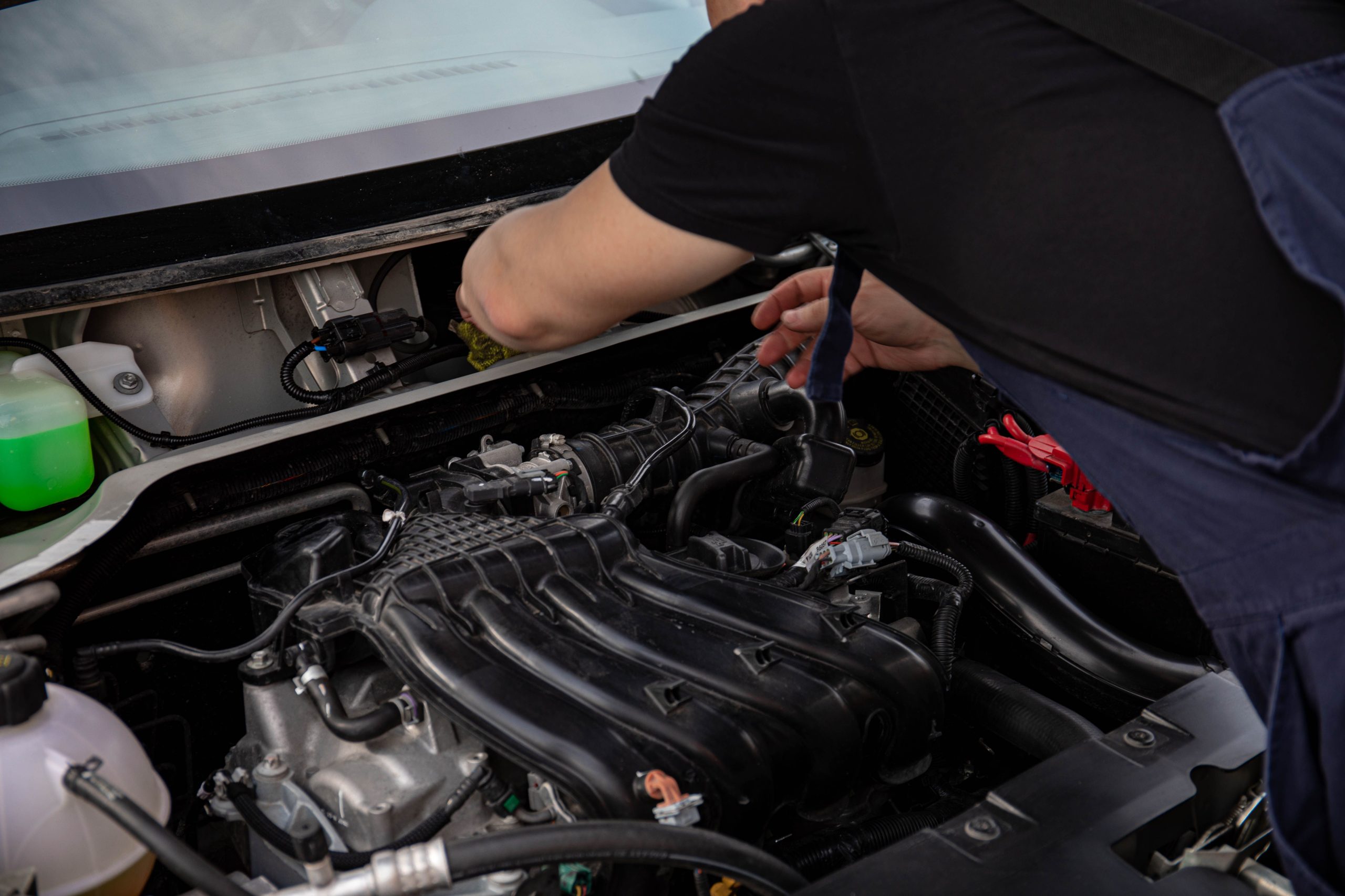 Close-up of a mechanic working on car engine. Ideal for automotive maintenance and repair themes. Gros plan d'un mécanicien travaillant sur un moteur de voiture. Idéal pour les thèmes d'entretien et de réparation automobile.