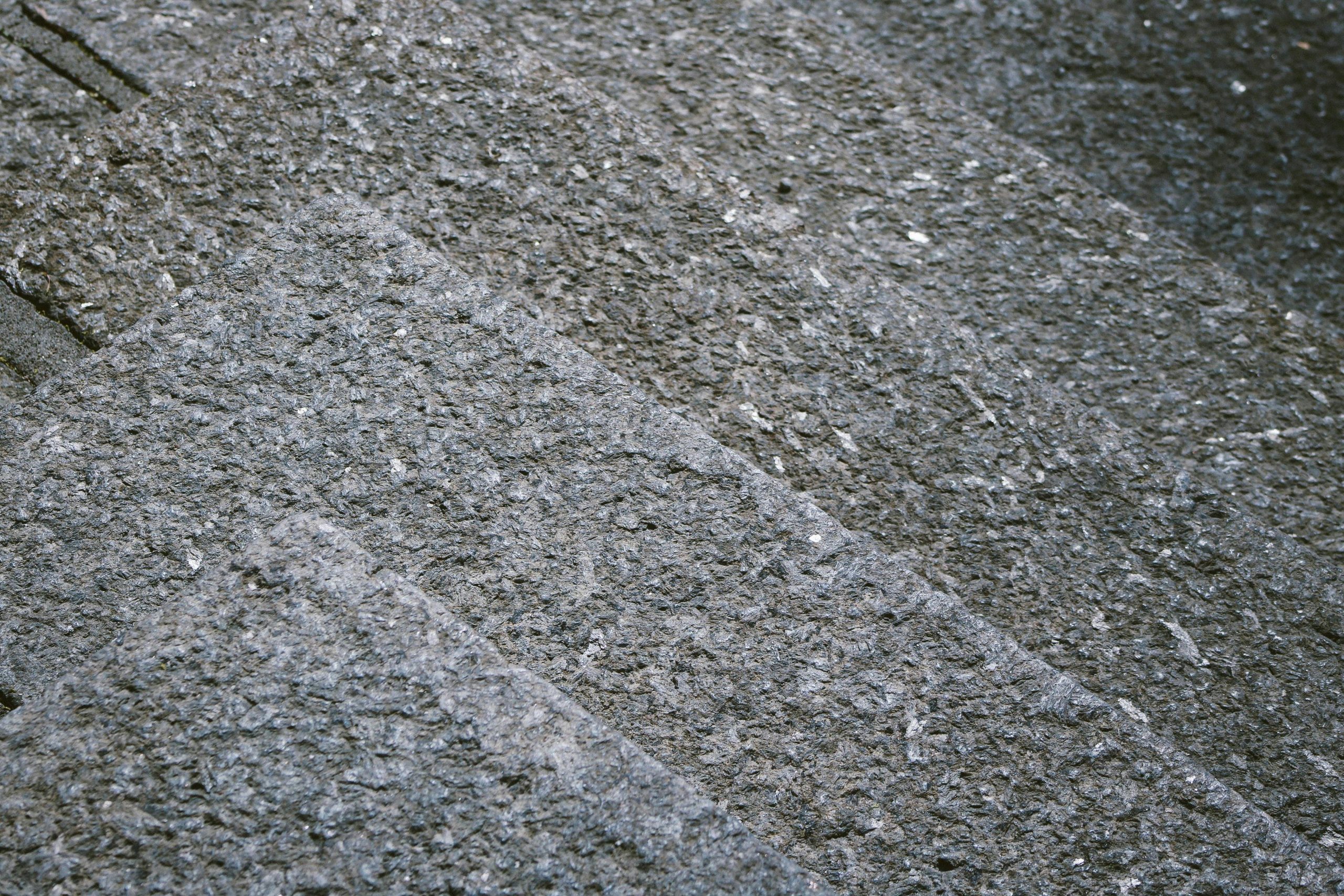 Close-up of textured granite steps showcasing a rough, gray stone surface. Gros plan des marches de granit texturé mettant en évidence une surface de pierre grise rugueuse.