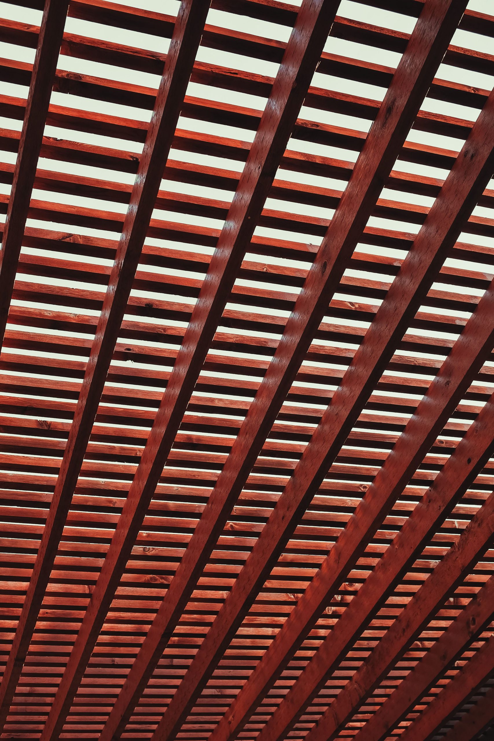 An intricate design featuring diagonal wooden beams creating a geometric ceiling pattern. Un design complexe présentant des poutres en bois diagonales créant un motif de plafond géométrique.