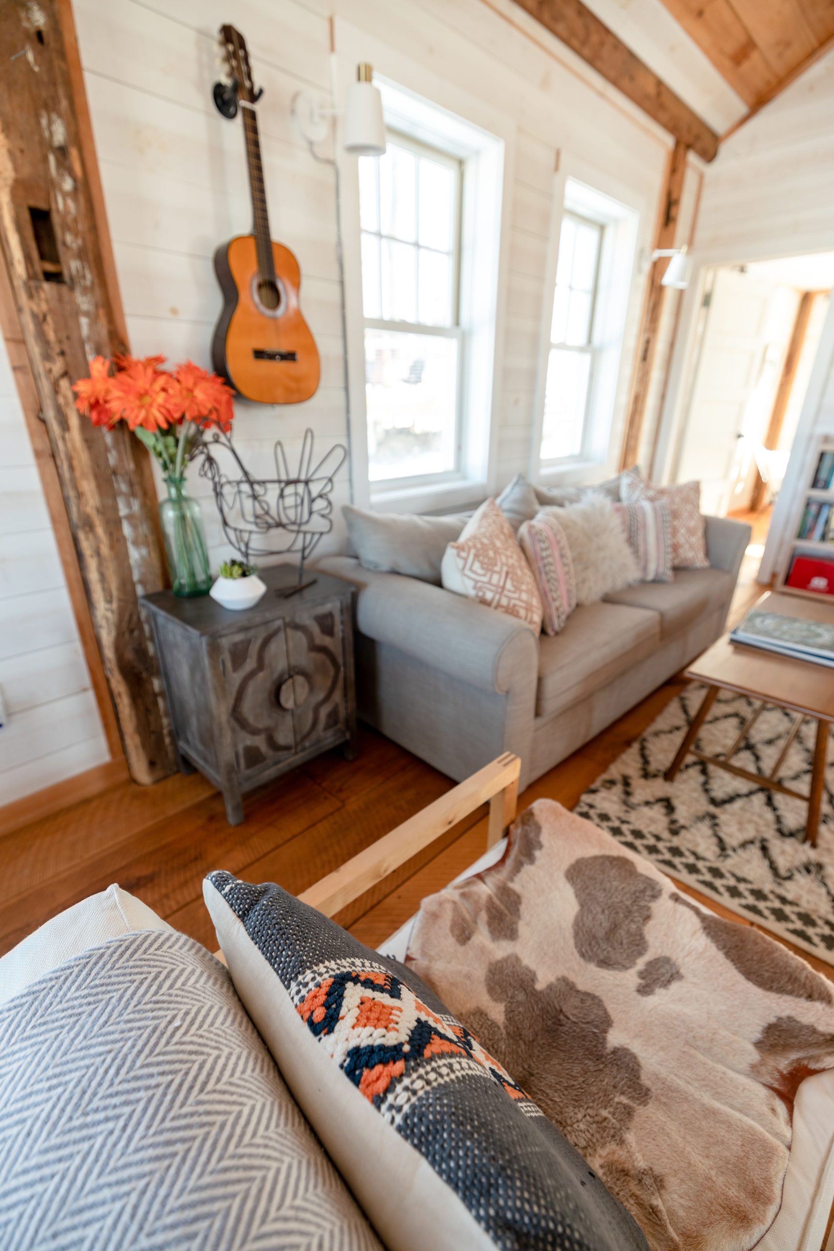 Salon chaleureux et accueillant avec décoration rustique, présentant une guitare et des fleurs vibrantes.