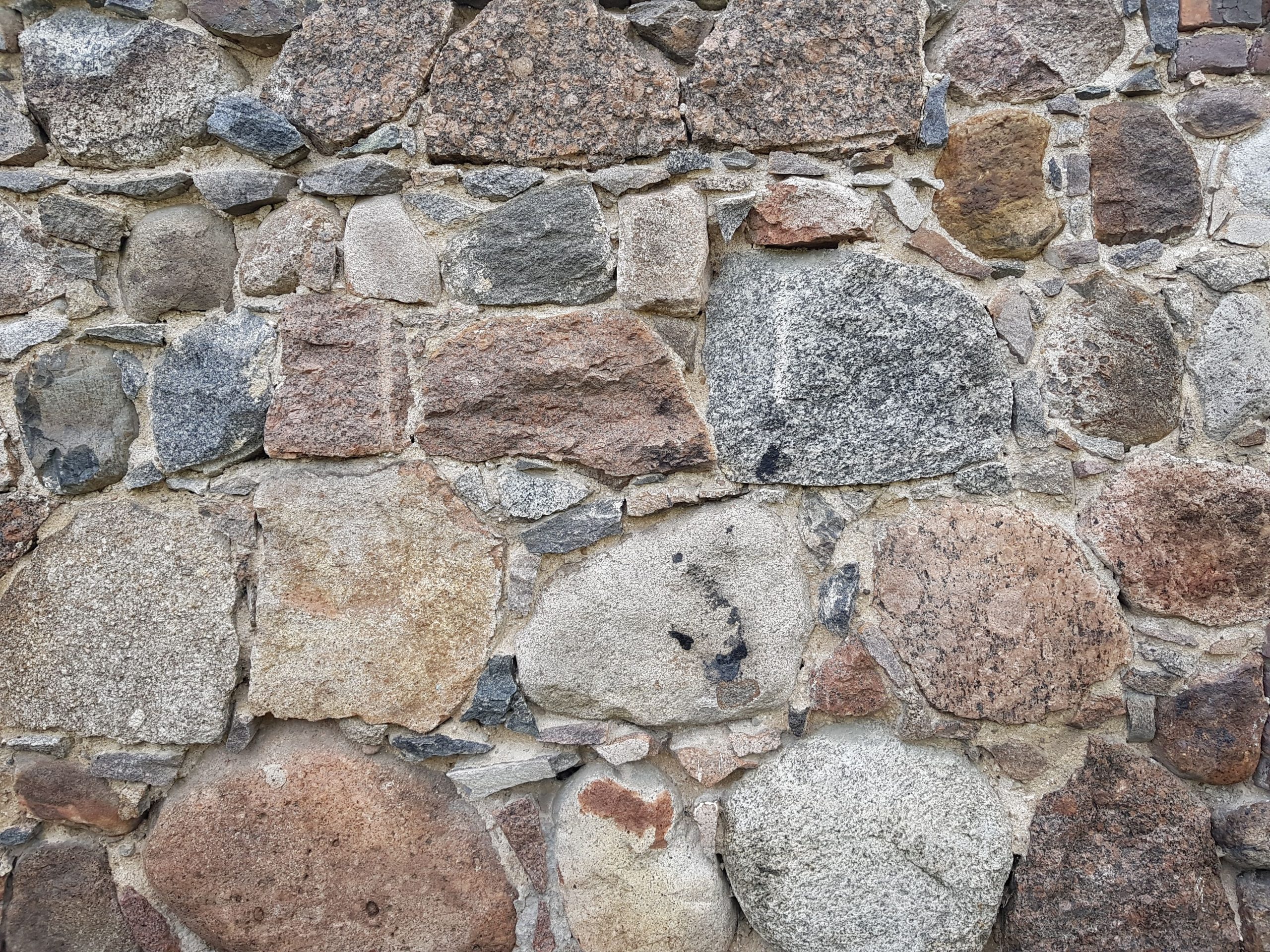 Close-up of a natural stone wall showcasing textures and earthy tones, ideal for design use. Gros plan d'un mur en pierre naturelle mettant en avant les textures et les tons terreux, idéal pour une utilisation en design.