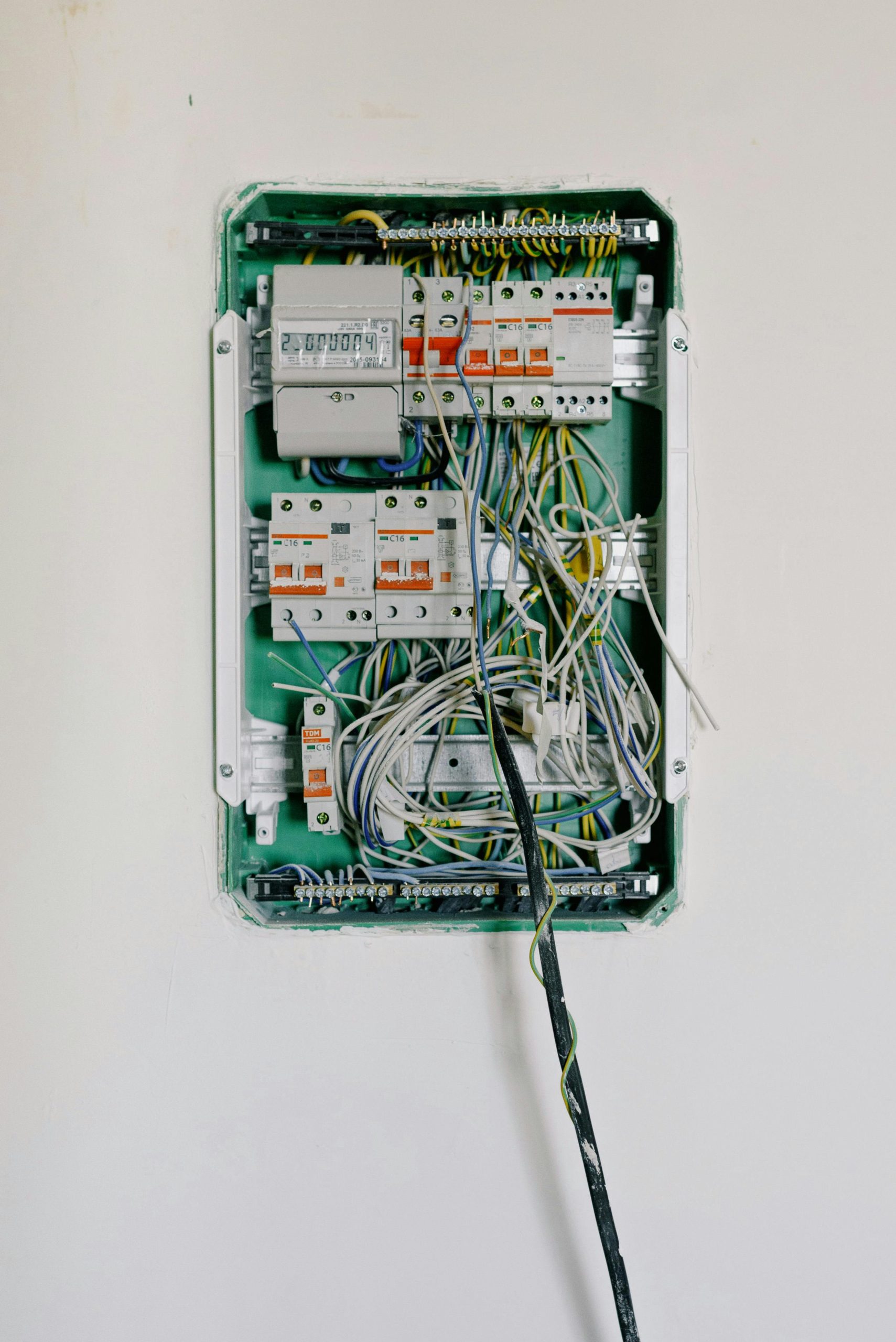 Switchboard with wires connected to electrical switches with circuit breakers installed on white wall Tableau de distribution avec des fils connectés à des interrupteurs électriques avec disjoncteurs installés sur un mur blanc