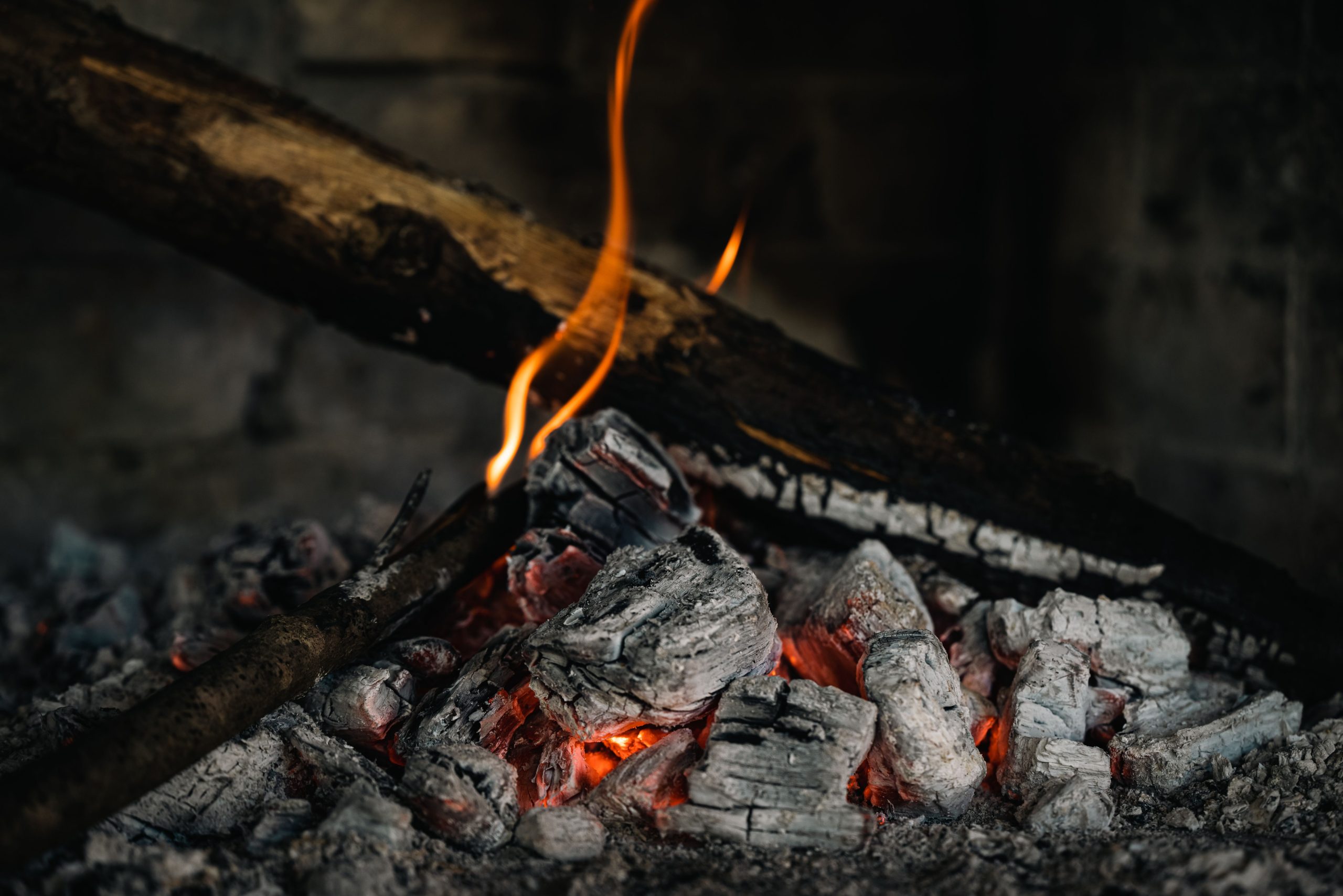 A detailed view of hot embers and burning firewood, creating a warm atmosphere. Une vue détaillée des braises chaudes et du bois de chauffage en feu, créant une atmosphère chaleureuse.