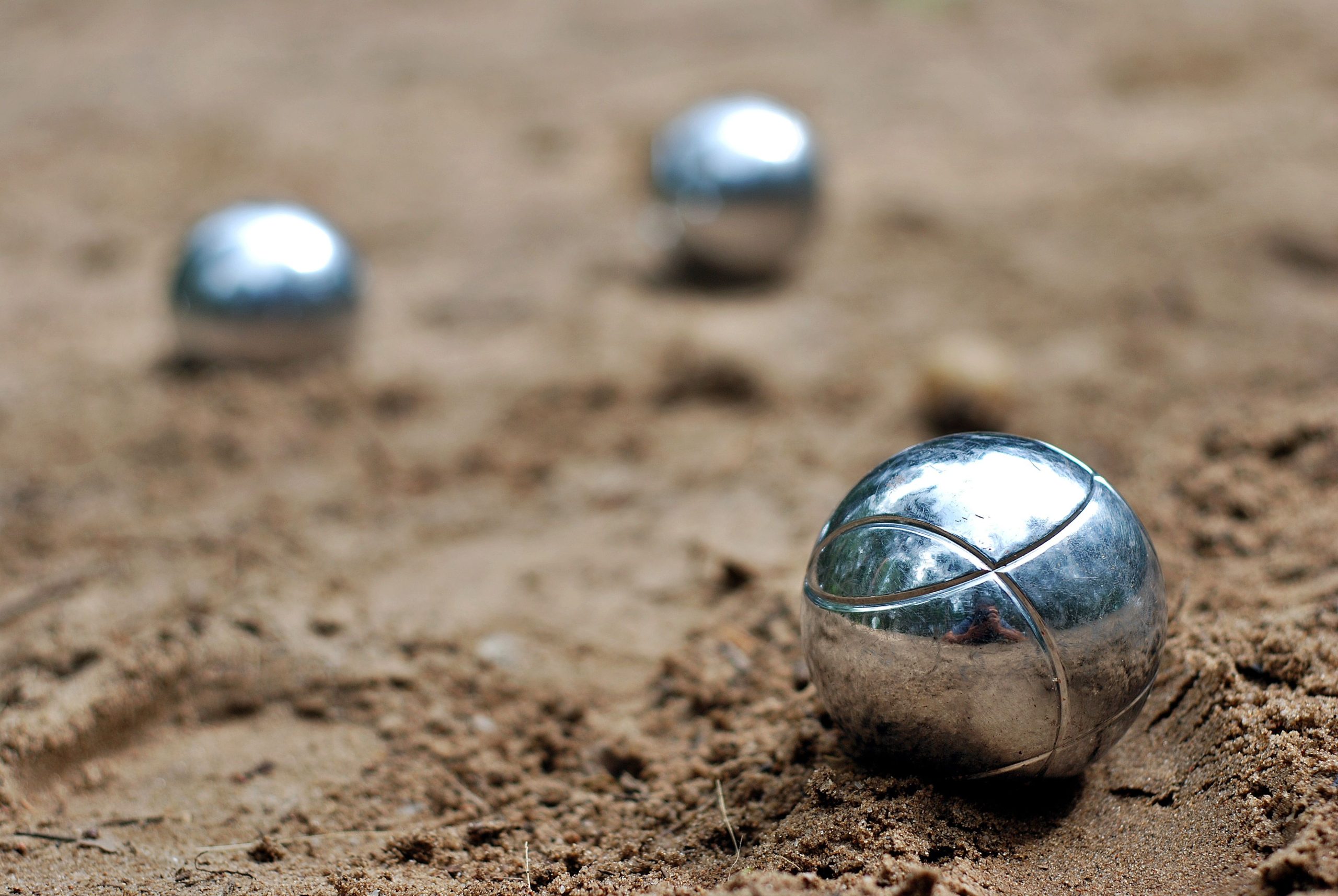 Close-up of shiny petanque balls on a sandy beach. Perfect for outdoor and leisure themes. Gros plan sur des boules de pétanque brillantes sur une plage de sable. Parfait pour les thèmes de loisirs et plein air.