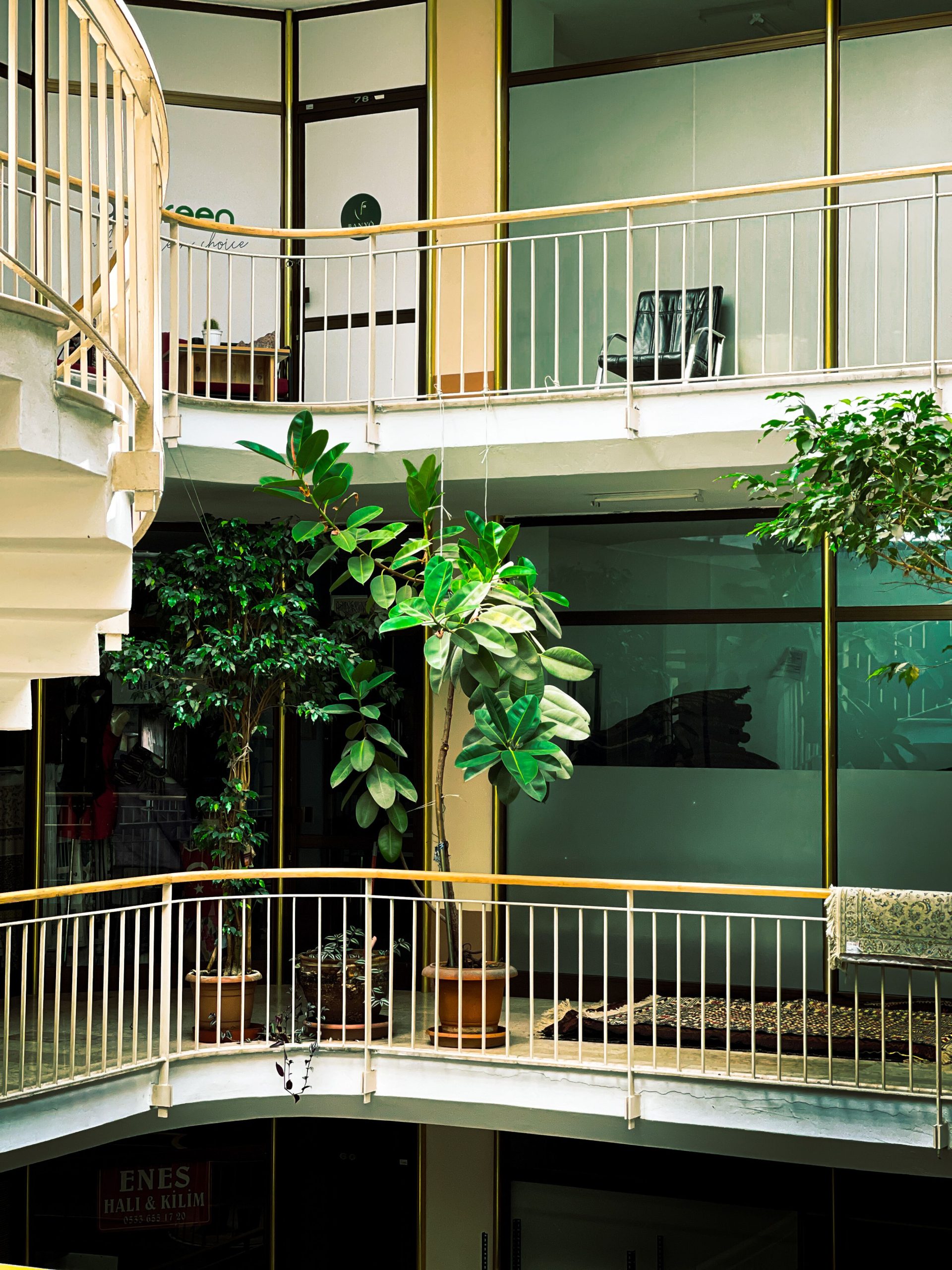 Contemporary atrium featuring plants and mezzanine levels in an urban residential building. Atrium contemporain avec des plantes et des niveaux de mezzanine dans un immeuble résidentiel urbain.