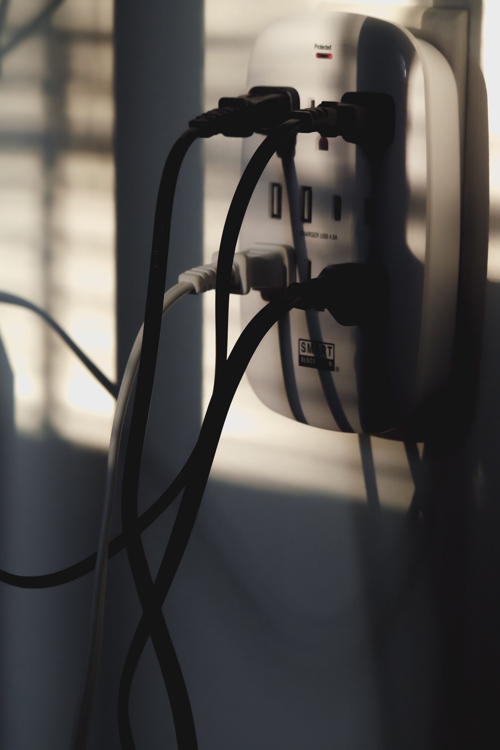 Multiple charging cables plugged into a wall outlet, showcasing energy connectivity. Plusieurs câbles de recharge branchés sur une prise murale, mettant en avant la connectivité énergétique.