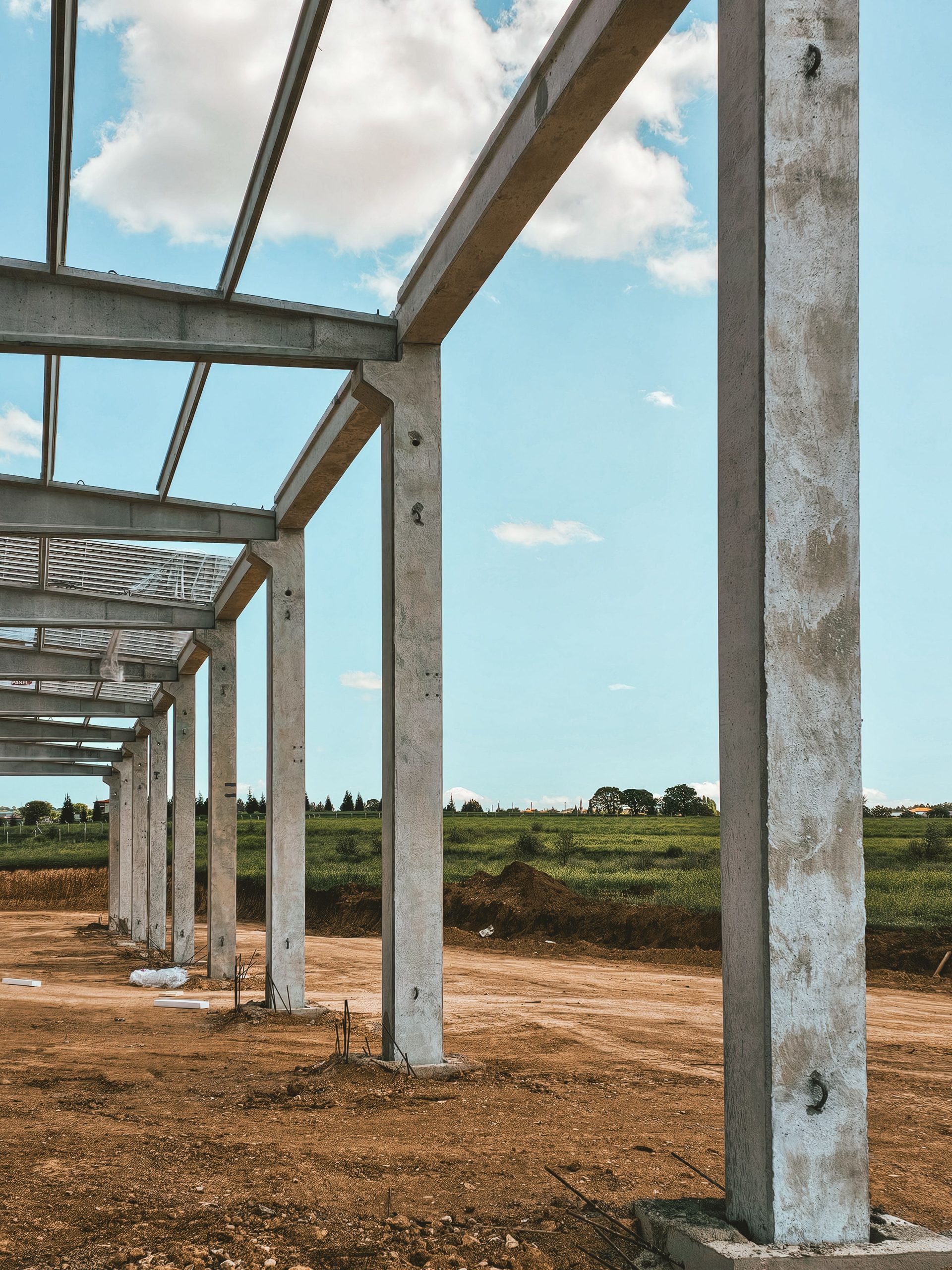 Concrete pillars in a rural setting form part of a new building structure under construction. Des piliers en béton dans un cadre rural font partie d'une nouvelle structure de bâtiment en construction.