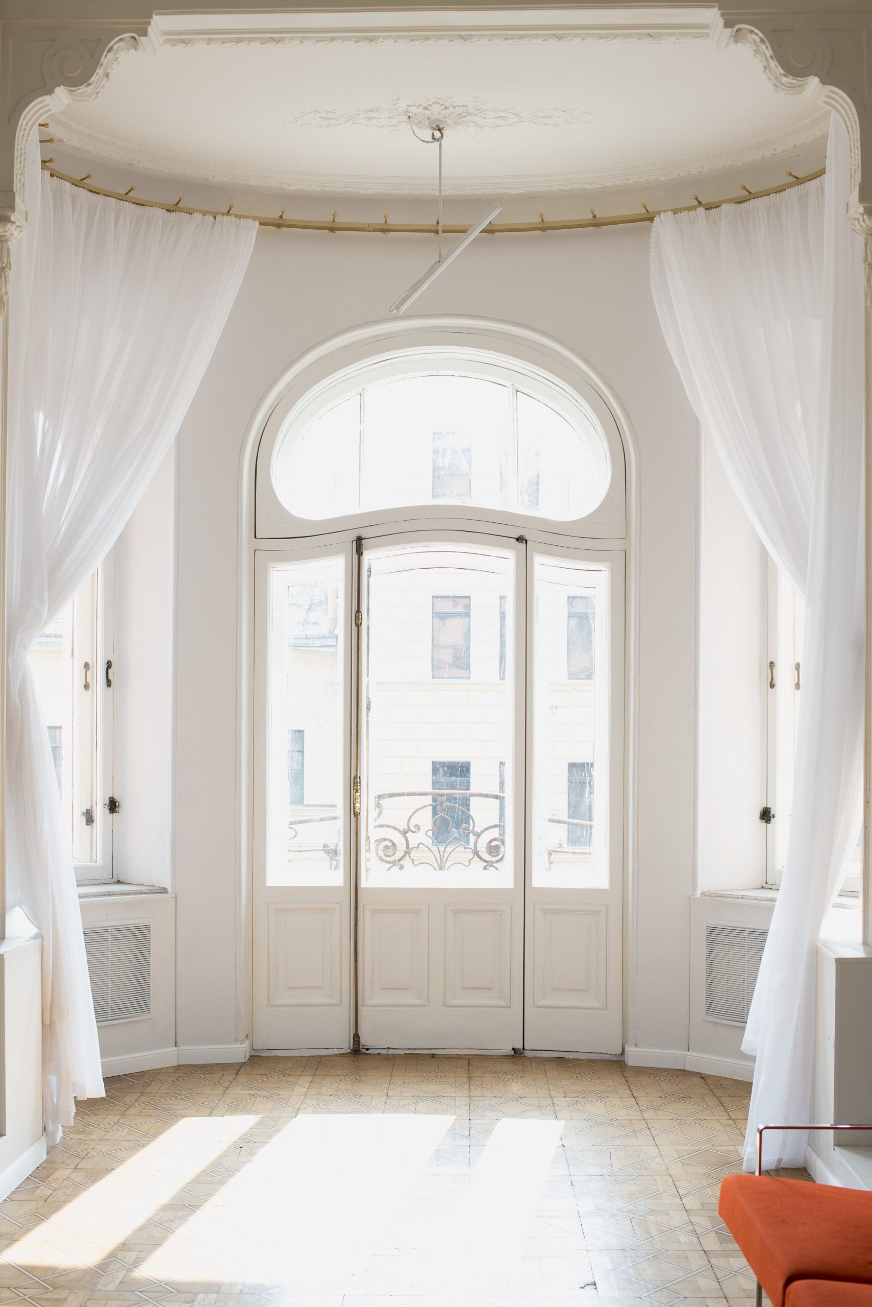 Bright and classic indoor view featuring elegant white French doors adorned with sheer white curtains. Vue intérieure lumineuse et classique mettant en avant des portes françaises blanches élégantes ornées de rideaux blancs translucides.